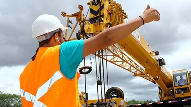 Profissional em obra com guindaste, representando habilidades de rigger sinaleiro